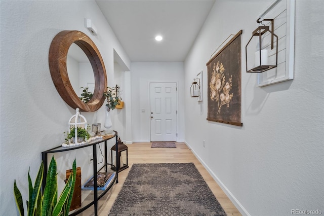 hallway with light wood finished floors, baseboards, and recessed lighting