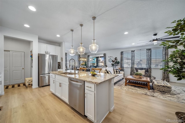 kitchen with white cabinets, light wood-style floors, stainless steel appliances, and a sink