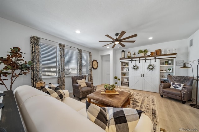 living room featuring recessed lighting, a ceiling fan, visible vents, and light wood-style flooring