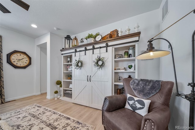 sitting room with recessed lighting, visible vents, light wood finished floors, and baseboards