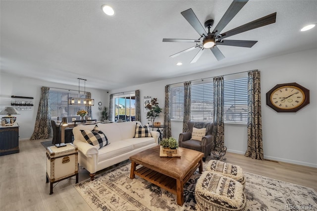 living area featuring a ceiling fan, baseboards, recessed lighting, and light wood-style floors