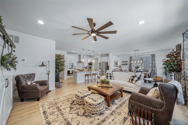 living area featuring recessed lighting, light wood-type flooring, visible vents, and a ceiling fan
