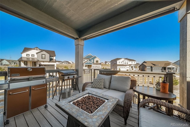 wooden terrace featuring a grill, an outdoor living space with a fire pit, and a residential view