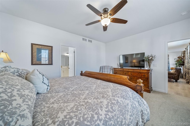 carpeted bedroom with ensuite bath, baseboards, a ceiling fan, and visible vents