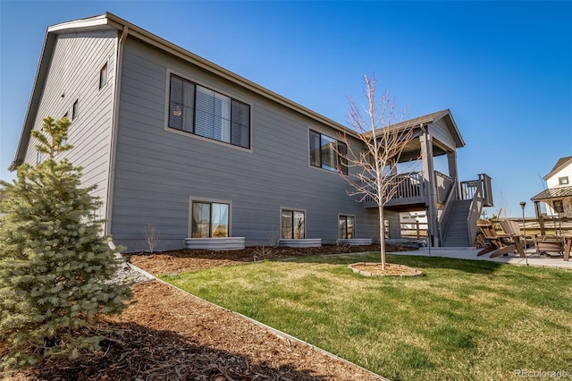 rear view of property featuring a lawn, stairs, a patio area, and a deck