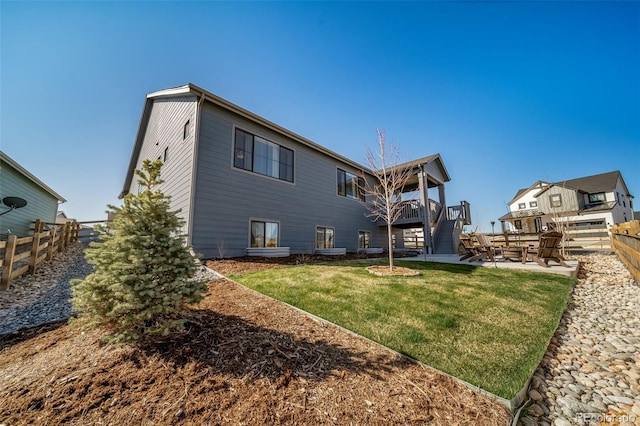 back of house featuring a fenced backyard, a wooden deck, a patio area, a lawn, and stairs