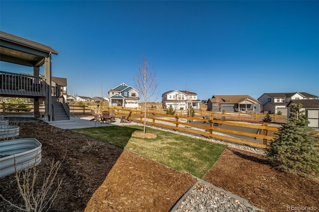 view of yard with a fenced backyard, stairs, and a residential view