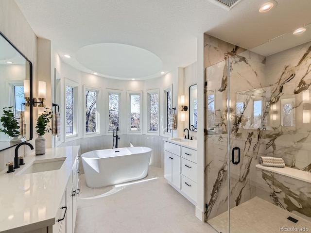 full bathroom with recessed lighting, two vanities, a sink, a freestanding bath, and a marble finish shower