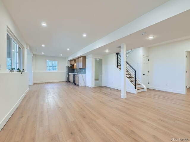 unfurnished living room with baseboards, light wood finished floors, and stairs