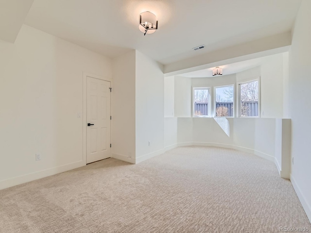 empty room featuring visible vents, light carpet, and baseboards