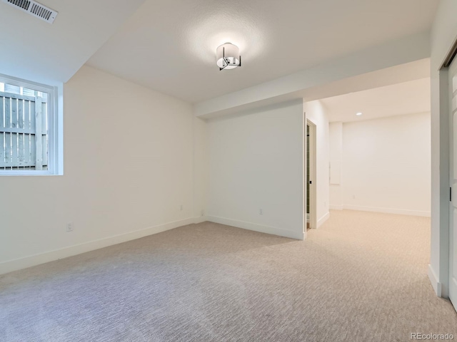 empty room featuring visible vents, light carpet, and baseboards