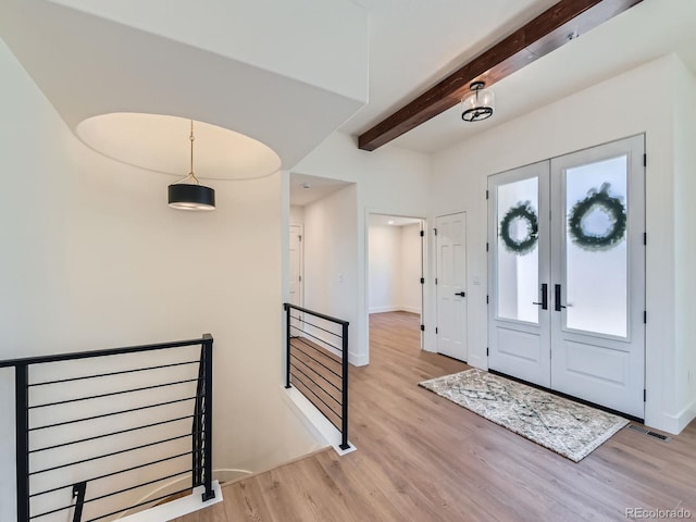 foyer entrance featuring french doors, light wood finished floors, visible vents, beamed ceiling, and baseboards