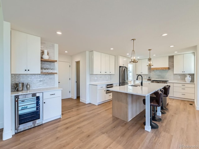 kitchen featuring beverage cooler, high end refrigerator, a sink, light wood-type flooring, and open shelves