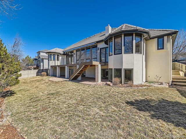 back of house featuring a chimney, stucco siding, fence, a tiled roof, and stairs