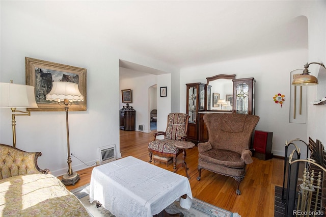 living room with visible vents, arched walkways, baseboards, and wood finished floors