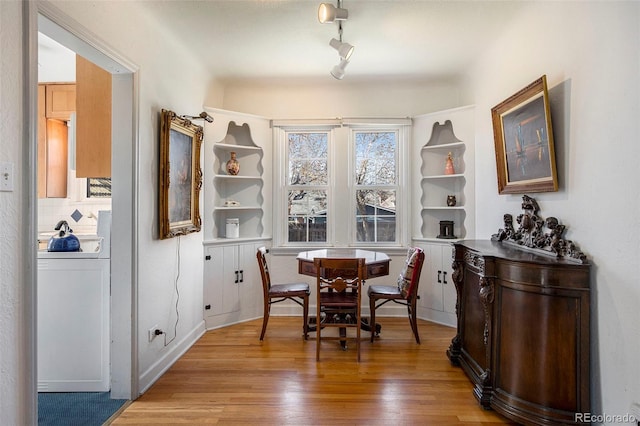 dining area featuring washer / dryer, rail lighting, and light wood-style floors