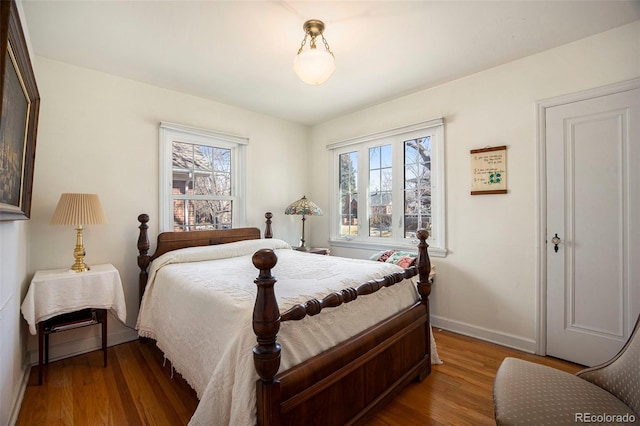 bedroom with baseboards, multiple windows, and wood finished floors