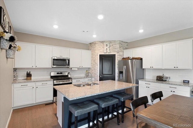 kitchen with a sink, decorative backsplash, appliances with stainless steel finishes, and white cabinetry