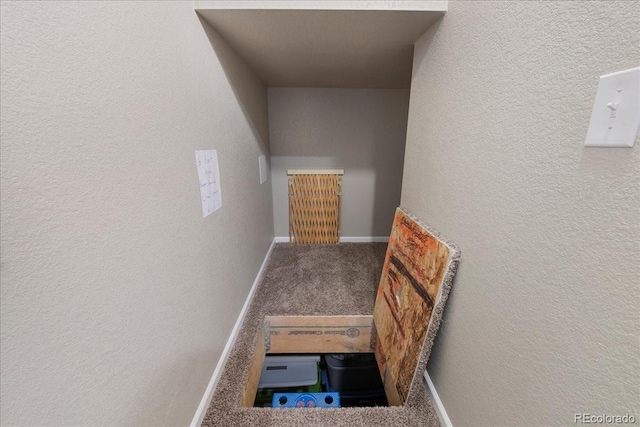 stairway featuring baseboards, carpet flooring, and a textured wall