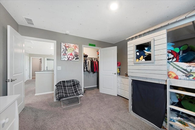 bedroom featuring a walk in closet, carpet, a closet, and visible vents