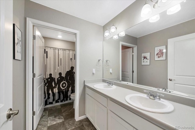 bathroom with double vanity, a sink, baseboards, and toilet