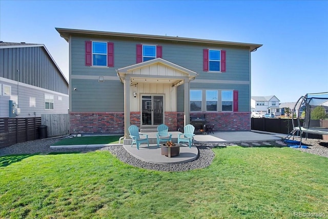 back of property featuring brick siding, a fenced backyard, a trampoline, and a patio