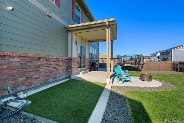 view of yard featuring a trampoline, a patio area, and fence private yard