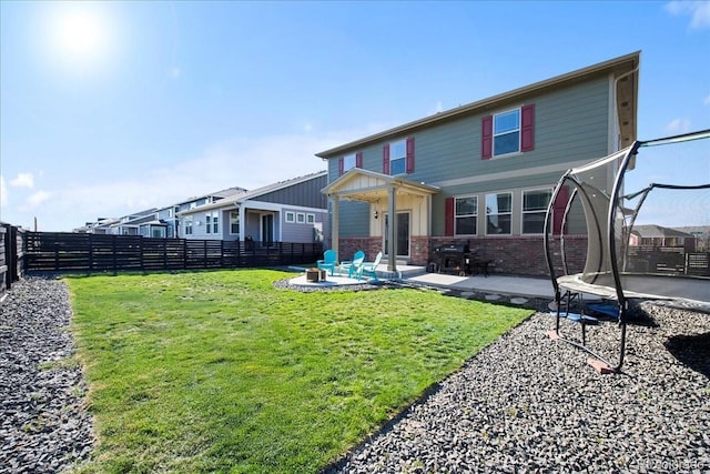 view of front of house featuring brick siding, a fenced backyard, a trampoline, and a patio area