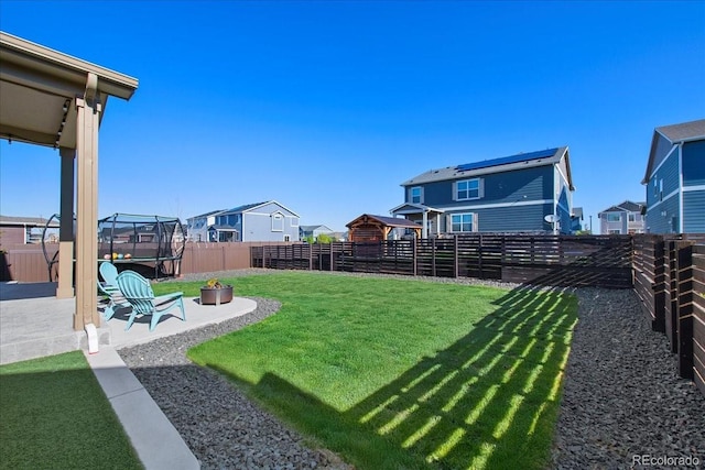 view of yard featuring a residential view, a trampoline, a fenced backyard, and a patio