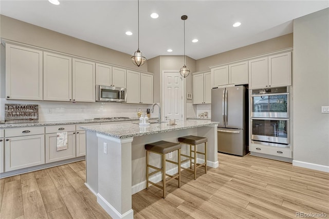 2932 Eagle Wing Way, Castle Rock, CO 80109 - kitchen featuring appliances with stainless steel finishes, light wood-style floors, tasteful backsplash, white cabinetry, and recessed lighting