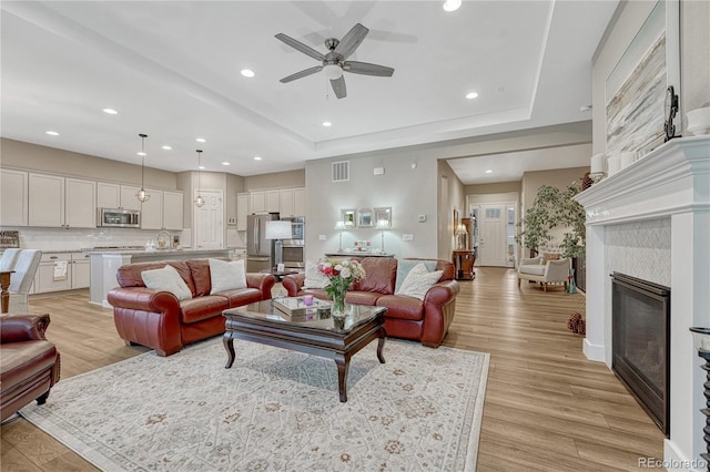 2932 Eagle Wing Way, Castle Rock, CO 80109 - living area with a ceiling fan, light wood-style floors, recessed lighting, a glass covered fireplace, and a raised ceiling