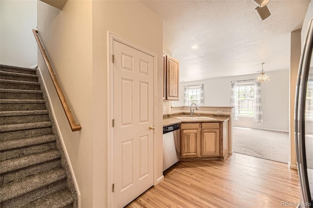 12704 Jasmine St Unit E, Thornton, CO 80602 - kitchen with stainless steel appliances, a peninsula, light wood-style flooring, light countertops, and a textured ceiling