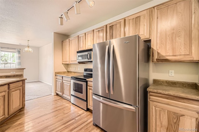 12704 Jasmine St Unit E, Thornton, CO 80602 - kitchen with appliances with stainless steel finishes, light brown cabinets, track lighting, light wood-style floors, and hanging light fixtures