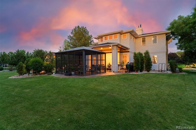 7 Sandpiper Cir, Thornton, CO 80241 - back of property at dusk with a yard, a patio, a chimney, a sunroom, and stucco siding