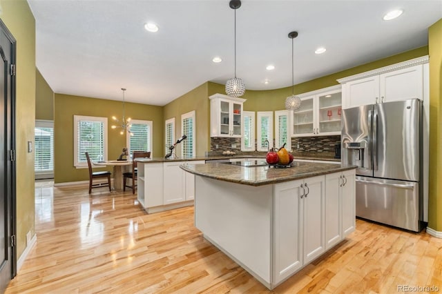 7 Sandpiper Cir, Thornton, CO 80241 - kitchen featuring stainless steel refrigerator with ice dispenser, a peninsula, decorative backsplash, light wood-style floors, and white cabinets