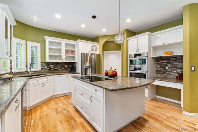 7 Sandpiper Cir, Thornton, CO 80241 - kitchen with appliances with stainless steel finishes, backsplash, light wood-type flooring, a kitchen island, and white cabinets