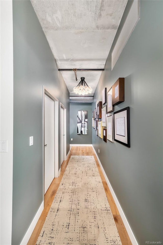 hall with light hardwood / wood-style floors and a notable chandelier