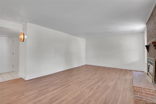 5419 E 113th Ave, Thornton, CO 80233 - unfurnished living room with a brick fireplace, light wood-type flooring, and baseboards