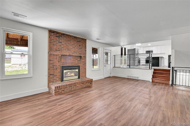 5419 E 113th Ave, Thornton, CO 80233 - unfurnished living room featuring baseboards, light wood-style flooring, a fireplace, and stairs
