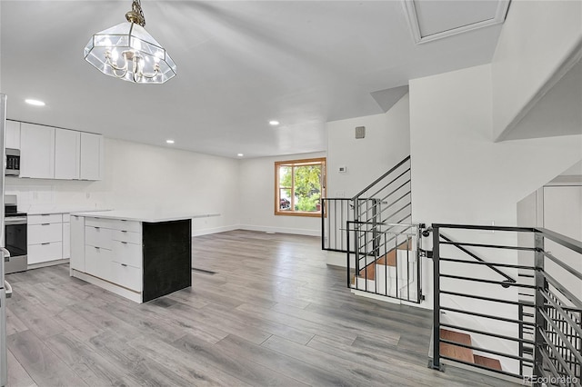5419 E 113th Ave, Thornton, CO 80233 - kitchen with appliances with stainless steel finishes, white cabinetry, light wood-style flooring, a kitchen island, and light countertops