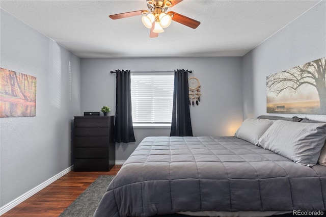 bedroom with a textured ceiling, ceiling fan, and dark wood-type flooring