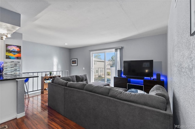 living room with a textured ceiling and dark hardwood / wood-style flooring