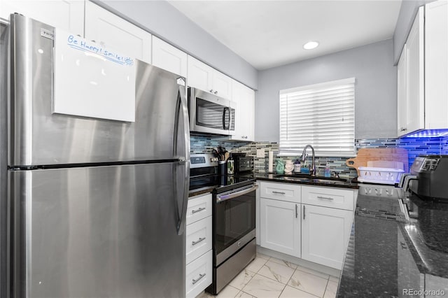 kitchen featuring backsplash, dark stone counters, stainless steel appliances, sink, and white cabinetry