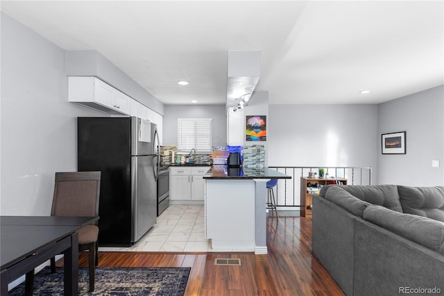 kitchen featuring tasteful backsplash, sink, light hardwood / wood-style flooring, white cabinets, and stainless steel refrigerator