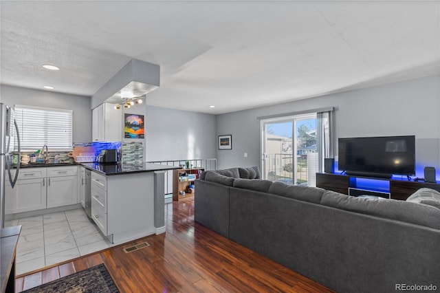 kitchen with dark countertops, backsplash, open floor plan, white cabinets, and a peninsula