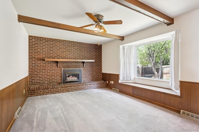 352 S Peoria Cir, Aurora, CO 80012 - unfurnished living room featuring a wainscoted wall, wooden walls, beam ceiling, ceiling fan, and a brick fireplace