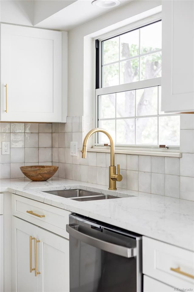 kitchen with white cabinets, dishwasher, light stone counters, and decorative backsplash