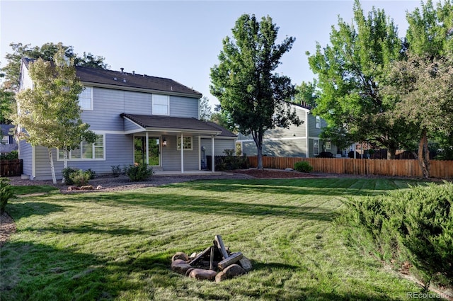 back of house with an outdoor fire pit, a patio area, and a lawn