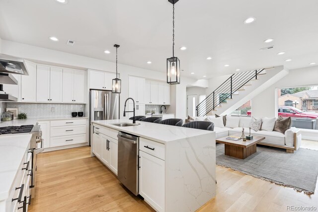 2040 W 45th Ave, Denver, CO 80211 - kitchen with appliances with stainless steel finishes, open floor plan, light wood-style floors, tasteful backsplash, and an island with sink