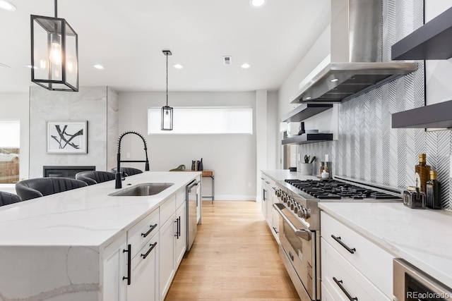2040 W 45th Ave, Denver, CO 80211 - kitchen with island range hood, appliances with stainless steel finishes, white cabinetry, light wood-style floors, and light stone countertops